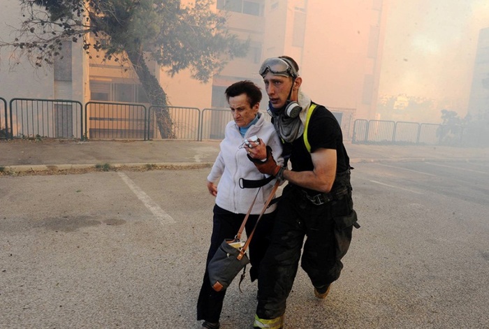 Фото: Reuters  Аврагч нэгэн эмэгтэйг аюулын бүсээр гарахад нь тусалж байгаа нь