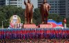 People carry flags in front of statues of North Korea founder Kim Il Sung (L) and late leader Kim Jong Il during a military parade marking the 70th anniversary of North Korea's foundation in Pyongyang