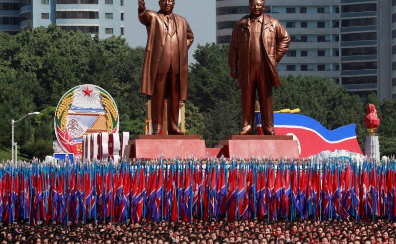 People carry flags in front of statues of North Korea founder Kim Il Sung (L) and late leader Kim Jong Il during a military parade marking the 70th anniversary of North Korea's foundation in Pyongyang