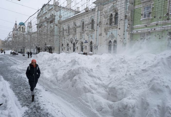 A woman walks past a heap of snow in central Moscow