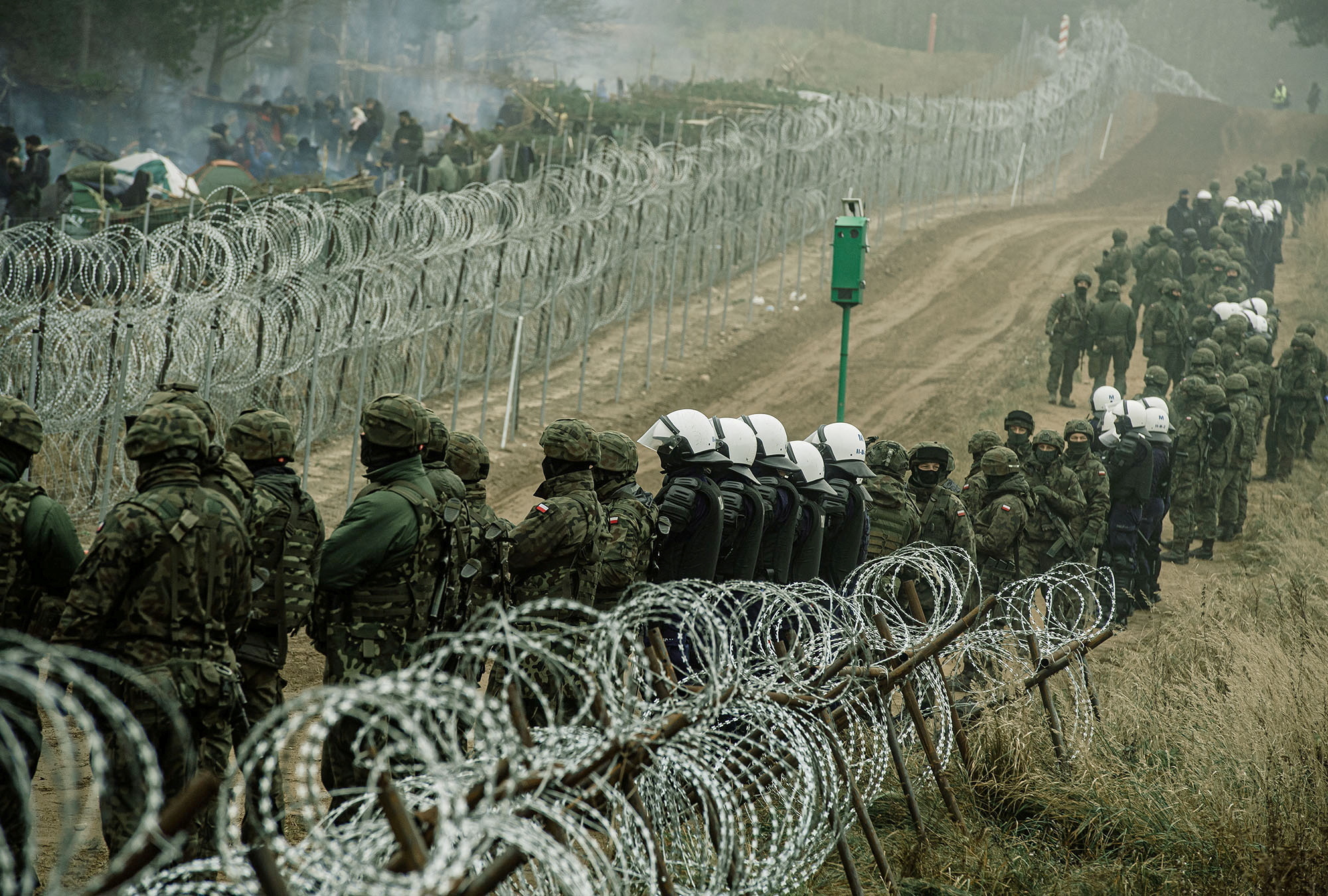 FILE PHOTO: Polish soldiers and police watch migrants at the Poland/Belarus border near Kuznica