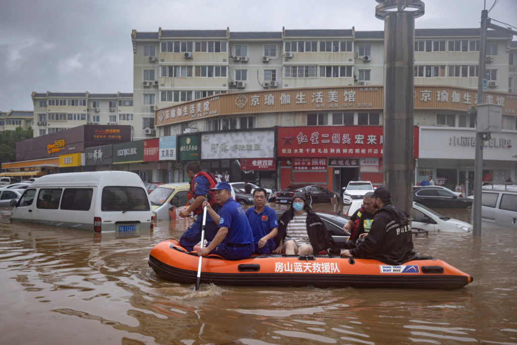 Rescue workers in a boat go through a flooded street in a neighbourhood where days of heavy rain from remnants of Typhoon Doksuri cause heavy damage in Beijing